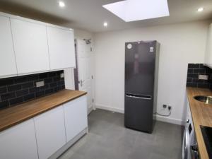 a kitchen with white cabinets and a black refrigerator at The Old Guest House, 249A Norbury Avenue in Norbury