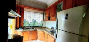 a kitchen with wooden cabinets and a refrigerator at Hilltop Greenview Residence Batu Caves Selayang in Batu Caves