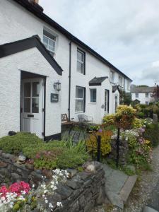 a white house with a garden and flowers at Spa Cottage in Braithwaite