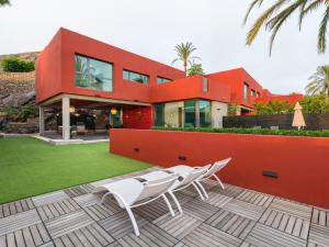 ein rotes Haus mit weißen Stühlen auf einer Terrasse in der Unterkunft Salobre Golf Villas Tabaibas in Salobre