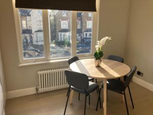 a dining room table with chairs and a vase with flowers at Splendid 2 Bed Flat with Private Terrace in Wimbledon - 2 The Queens in London