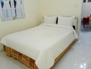 a large white bed with white sheets and pillows at Balqis Homestay Syariah III Nagari Salo Kec Baso Kab Agam in Baso