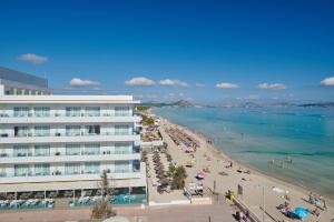 ein Strand mit einem großen Gebäude und Menschen darauf in der Unterkunft The Sea Hotel by Grupotel - Adults Only in Can Picafort