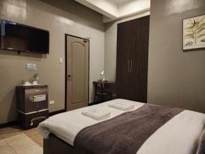 Grayhouse Inn Tagaytay في تاجيتاي: غرفة نوم بسرير وتلفزيون بشاشة مسطحة