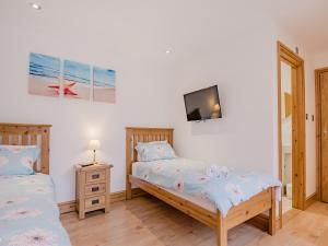 a bedroom with two beds and a tv on the wall at The Great South Barn - Ukc2527 in Trunch