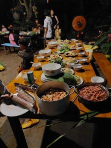 a long wooden table with many plates of food at The Lazy Farm-Garden Central Room in Mewal