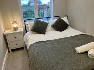 a bedroom with a bed with pillows and a window at Splendid 2 Bed Flat with Private Terrace in Wimbledon - 2 The Queens in London