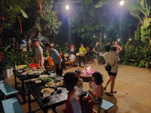 a group of people standing around a camp fire at The Lazy Farm-Garden Central Room in Mewal