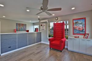 a red chair in a living room with a ceiling fan at Hotel 414 Anaheim in Anaheim