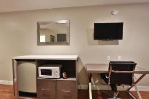 a desk with a microwave and a television on a wall at Hotel 414 Anaheim in Anaheim