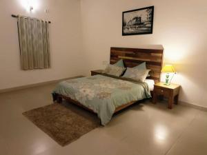 um quarto com uma cama e uma mesa com um candeeiro em The Road's End em Gonikoppal
