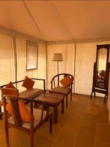 um quarto com quatro cadeiras, uma mesa e um candeeiro em Lakhina Heritage desert camp em Jaisalmer