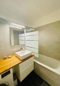 La salle de bains est pourvue d'un lavabo, d'un miroir et d'une baignoire. dans l'établissement Appartement résidence Les Faunes à La Baule, à La Baule