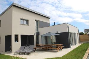 a white house with a picnic table and chairs at Villa de la plage des Amiets #piscine intérieure privée# les pieds dans l'eau in Cléder