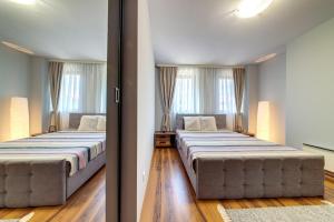 two beds in a room with two windows at Luxury Flat in Grand Resort Pamporovo in Pamporovo