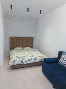 ein Schlafzimmer mit einem Bett und einem blauen Sofa in der Unterkunft ЖК Palladium/41 in Almaty