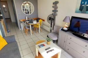 een kleine woonkamer met een tv en een tafel bij "FENÊTRE SUR MER" Appartement vue mer, 4 personnes, accès parc aquatique in Saint-Jean-dʼOrbetiers
