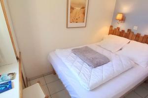 een kleine slaapkamer met een wit bed in een kamer bij "FENÊTRE SUR MER" Appartement vue mer, 4 personnes, accès parc aquatique in Saint-Jean-dʼOrbetiers