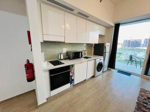 a kitchen with white cabinets and a large window at Furnished & Serviced Studio in Abu Dhabi