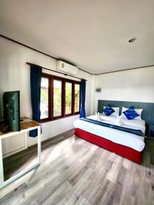 a bedroom with a bed with blue pillows and a television at Three Trees Samui Resort - Sarocha Villa in Lamai