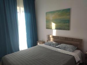 a bedroom with a bed with blue curtains and a window at Guest House Banuri in Kutaisi