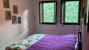 1 Schlafzimmer mit einem lila Bett und 2 Fenstern in der Unterkunft Leo Anfosso in Carpasio