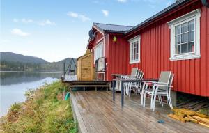 una casa roja con mesa y sillas en un muelle en Awesome Home In Follafoss With Lake View, 
