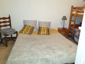 1 dormitorio con 1 cama con 2 almohadas y 1 silla en Maison Mornas, en Mornas