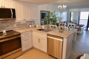 eine Küche mit weißen Schränken und ein Wohnzimmer in der Unterkunft Charming 2 Bed South End Beachfront Condo at Popular Seawinds in Henry Key