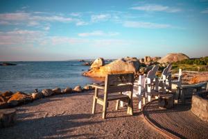 a group of chairs sitting on a beach near the water at Sea Shack in Paternoster