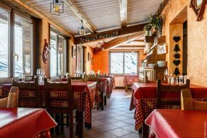 a restaurant with red tables and chairs and windows at Hotel Spa L'Equipe in Molines-en-Queyras
