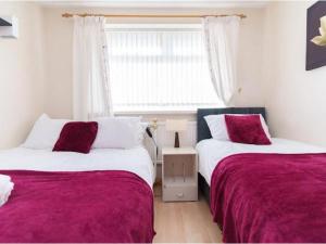 two beds in a room with a window at Alexander House Apartments in Leeds
