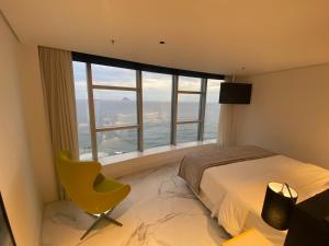 a bedroom with a bed and a yellow chair in front of a window at Hotel Nacional Rio de Janeiro in Rio de Janeiro