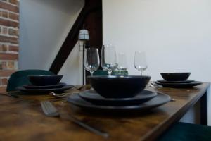 a wooden table with plates and wine glasses on it at Luxury Penthouse In Central Nottingham in Nottingham