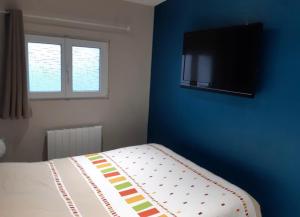 1 dormitorio con 1 cama y TV en una pared azul en Studio meublé marne la vallée / Disneyland, en Faremoutiers