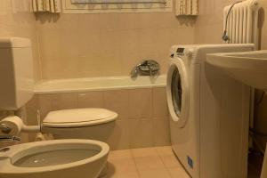 uma casa de banho com um WC e uma máquina de lavar roupa em Appartamenti Ladina em Campitello di Fassa