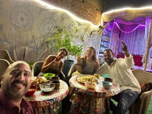 Jana Pyramids view inn في القاهرة: مجموعة من الناس يجلسون على طاولة مع الطعام