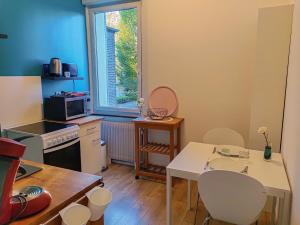 une cuisine avec une table et des chaises ainsi qu'une fenêtre dans l'établissement Le Cocon Bleu - Appartement Calme - Parking Gratuit - Fibre, à Arras