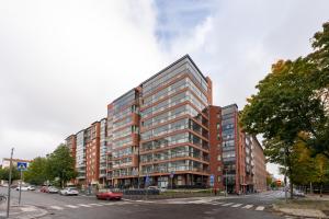 un edificio alto en una calle de la ciudad con coches aparcados en New 2BR Home with Sauna, Balcony & Great Location, en Tampere