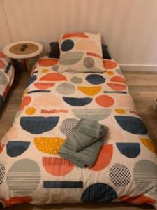 ein Bett mit einer Bettdecke und Kissen darauf in der Unterkunft Studio confortable aux portes de Bordeaux et Médoc in Ludon-Médoc