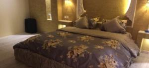 una camera da letto con un grande letto con un piumone marrone di شاليه غرناطة a Al Khabrāʼ