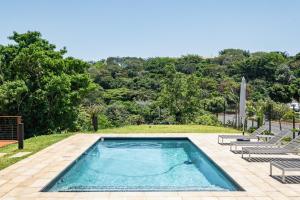 a swimming pool with two lounge chairs and trees at The Tyne Luxury Apartments in Durban