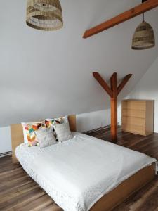 a bedroom with a bed with white sheets and wooden floors at Sielskie Klimaty in Marcinowice