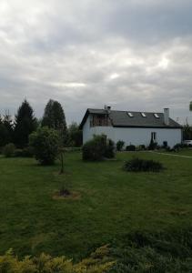 una casa blanca con paneles solares en un campo en Sielskie Klimaty, en Marcinowice