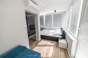 ein kleines Schlafzimmer mit einem Bett und Fenstern in der Unterkunft Silver One Apartments in Danzig
