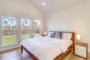 a white bedroom with a bed and two windows at Gorgeous Harrison Getaway with Patio and Kayak! in Harrison