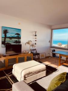 een woonkamer met een bank en een tv bij Sunset Beach House in Zambujeira do Mar