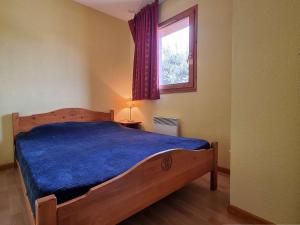 a bedroom with a bed with a blue comforter and a window at Appartement Le Dévoluy, 2 pièces, 6 personnes - FR-1-525-272 in Le Dévoluy