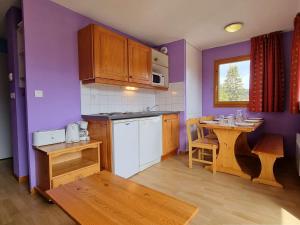 kuchnia z fioletowymi ścianami, stołem i stołem oraz tableablish w obiekcie Appartement Le Dévoluy, 2 pièces, 6 personnes - FR-1-525-272 w mieście Dévoluy