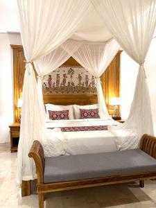 een slaapkamer met een groot bed met een baldakijn bij Gyanesh Villa in Ubud
